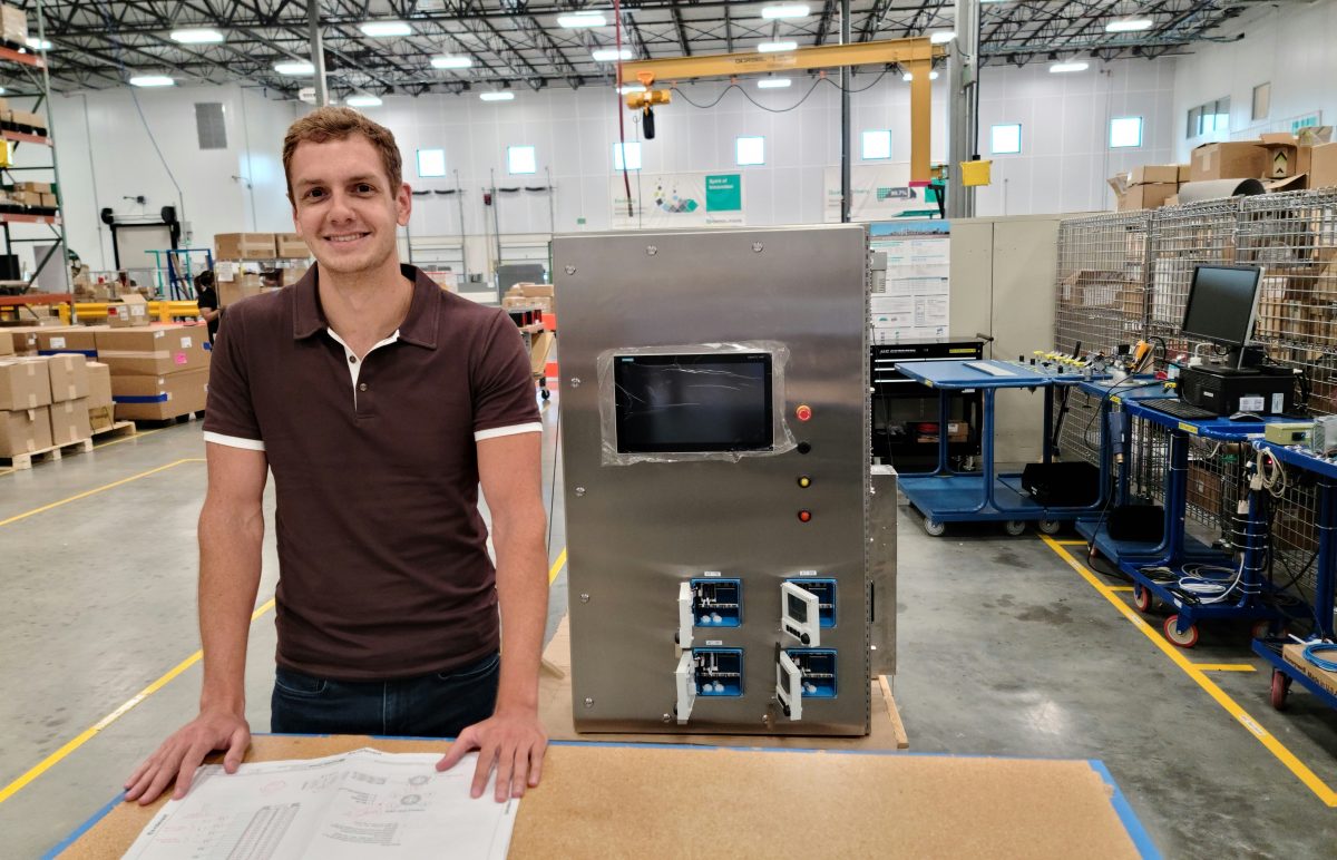 Alex, Order Unit Manager at Pepperl+Fuchs, is in the Solution Engineering Center. Various devices and boxes can be seen behind him.