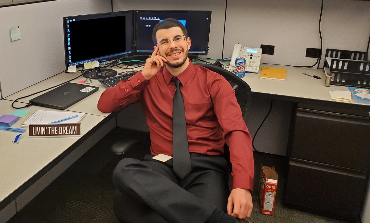 Donald, Business Development Specialist, is at his workplace at Pepperl+Fuchs Comtrol. He sits relaxed on his office chair, looking at the camera, while in the background, his desk and two monitors are visible.
