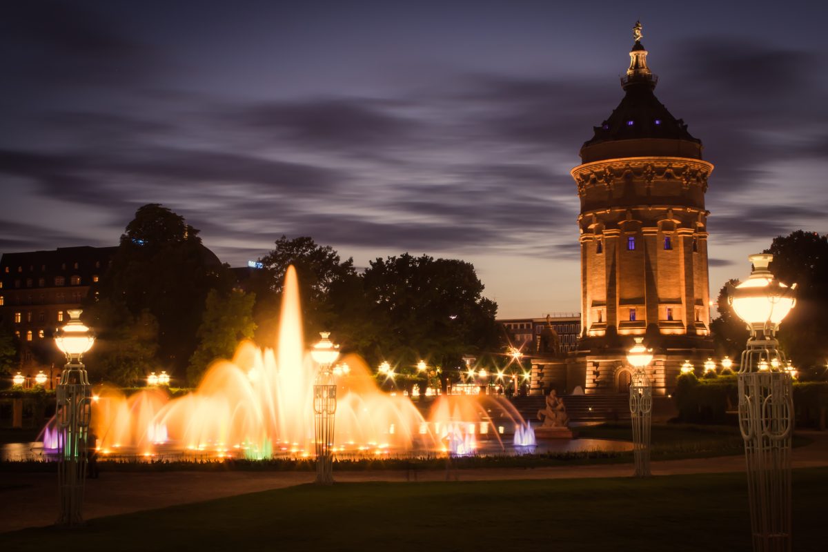 Mannheim bei Nacht. Rechts sieht man den Wasserturm und links einen leuchtenden Springbrunnen.