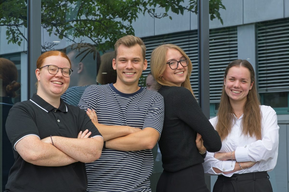 Hier sind vier unserer Auszubildenden bzw. dual Studierenden vor dem Pepperl+Fuchs Gebäude in Mannheim zu sehen. Sie stehen nebeneinander an die Gebäudewand gelehnt und verschränken die Arme. Dabei lächeln sie in die Kamera.