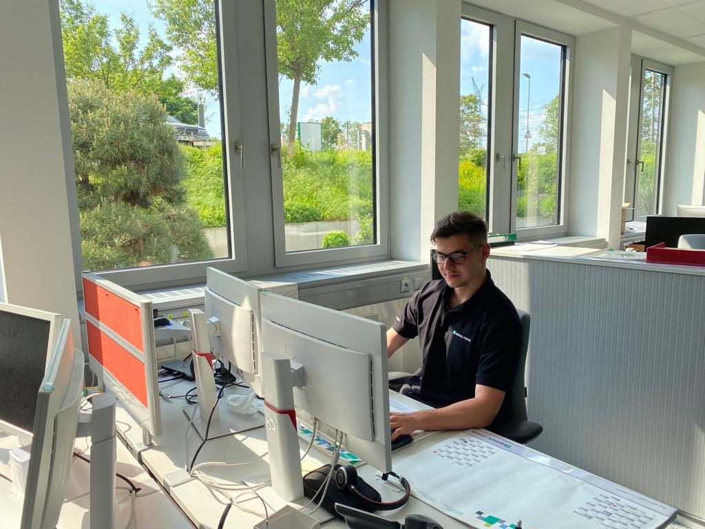 Timo, Auszubildender als Fachinformatiker für Systemintegration, sitzt hinter zwei Bildschirmen an seinem Arbeitsplatz bei Pepperl+Fuchs.