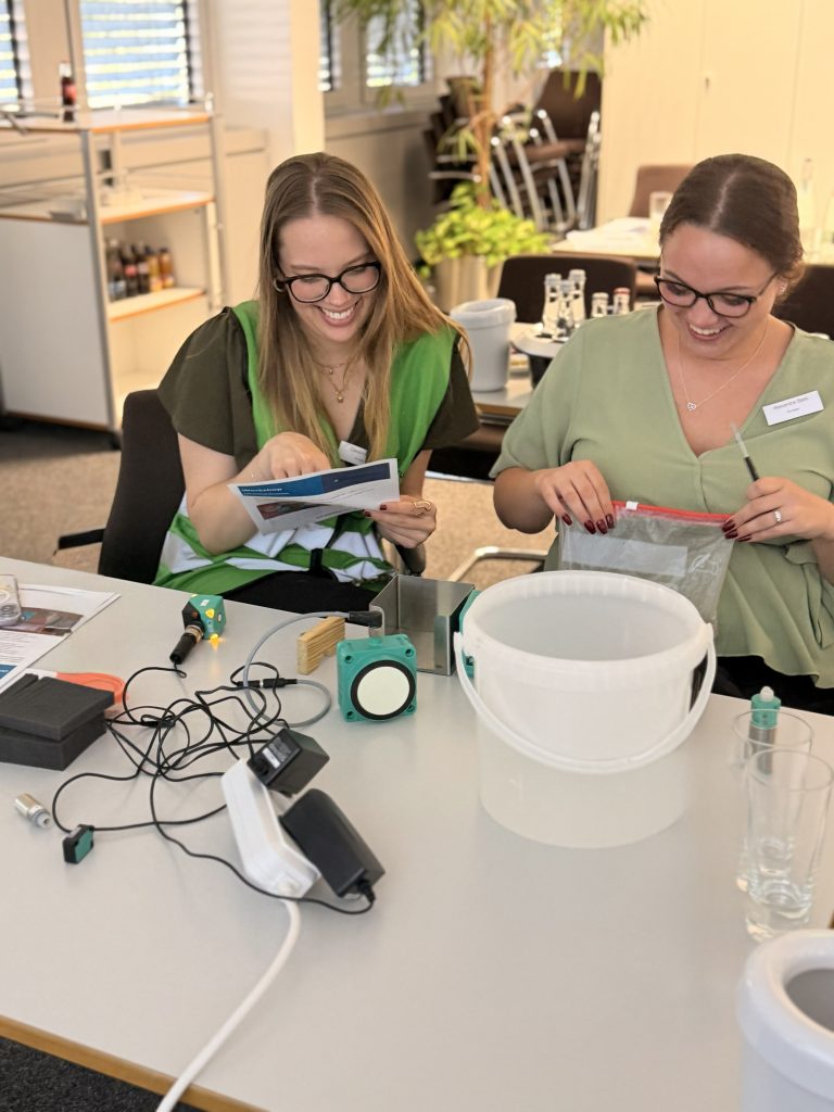 Zwei Teilnehmerinnen der Sonepar Azubitage sitzen am Tisch und werden mit Pepperl+Fuchs Produkten aktiv.