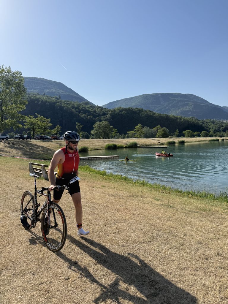 Marco schiebt sein Fahrrad neben einem See entlang.